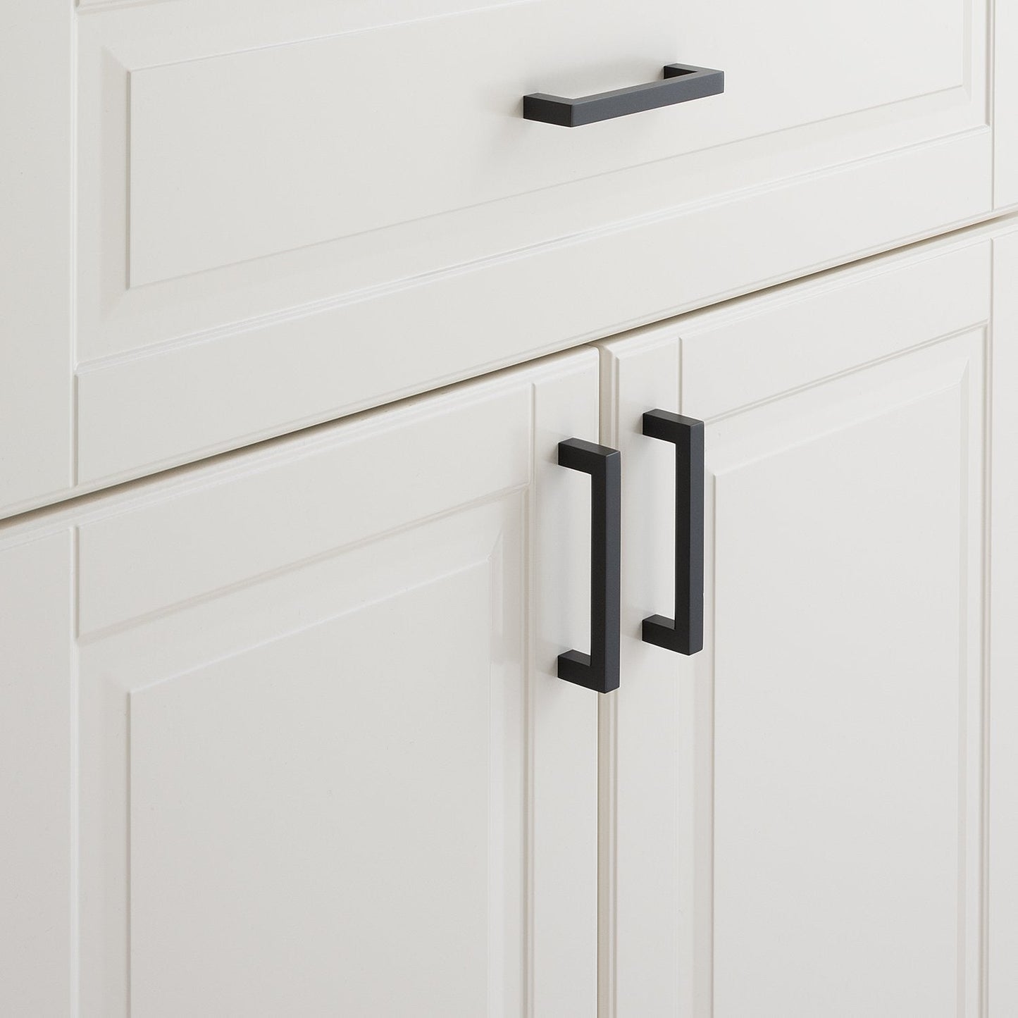 Close-up view of Edgecliff Pull showcasing its black finish on white paneled cabinets