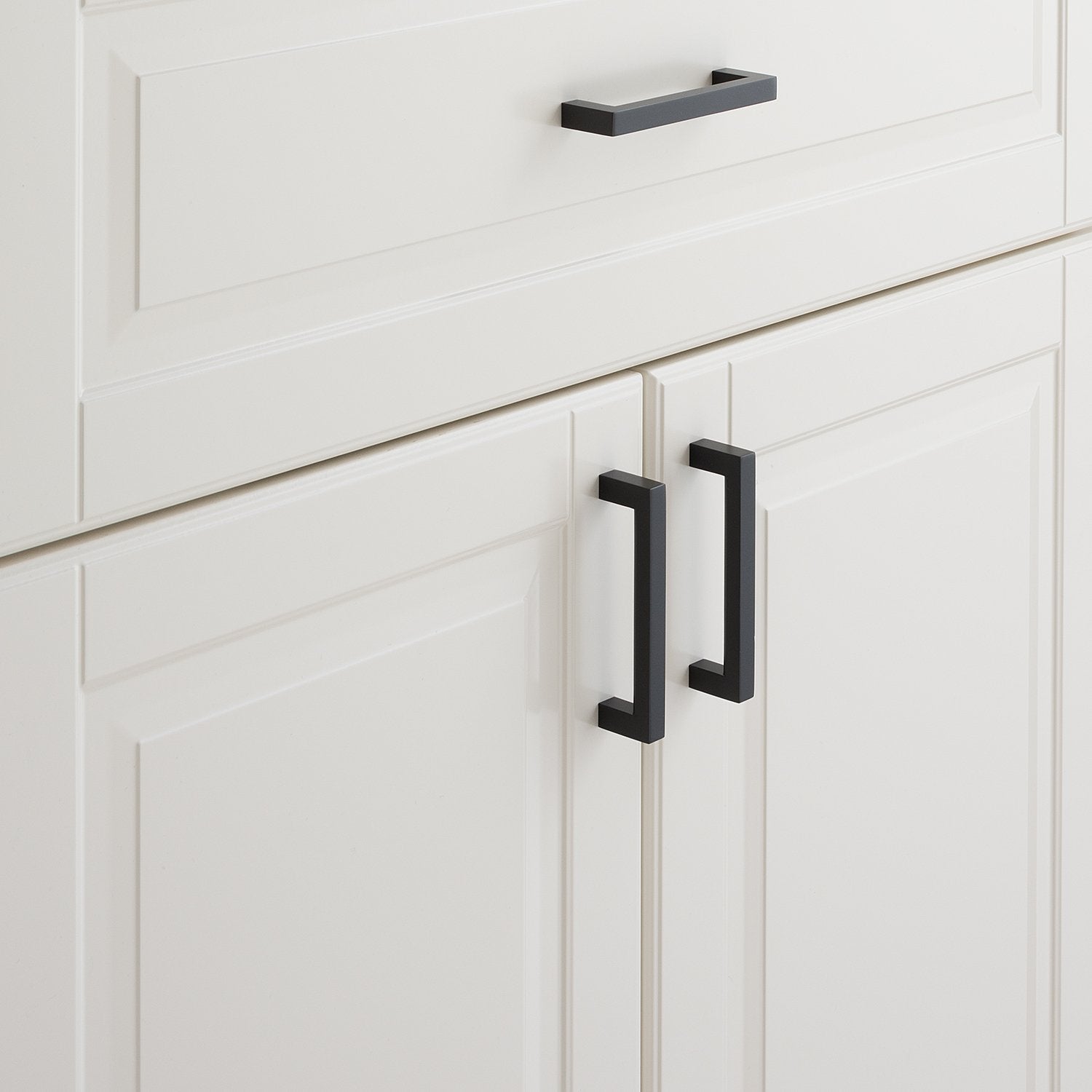 Close-up view of Edgecliff Pull showcasing its black finish on white paneled cabinets