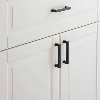 Close-up view of Edgecliff Pull showcasing its black finish on white paneled cabinets
