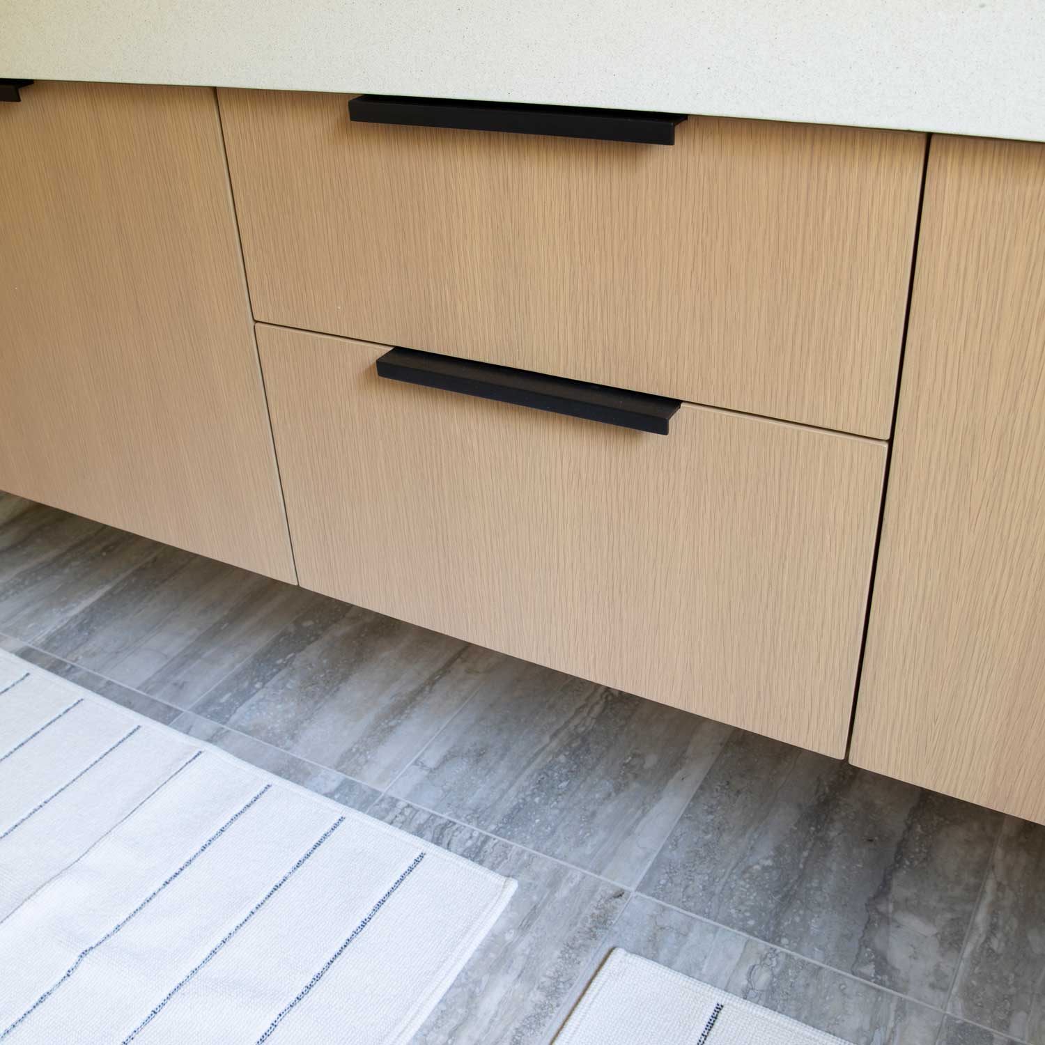 Front view of Ledge Pull showcasing black bar design on light wood cabinetry
