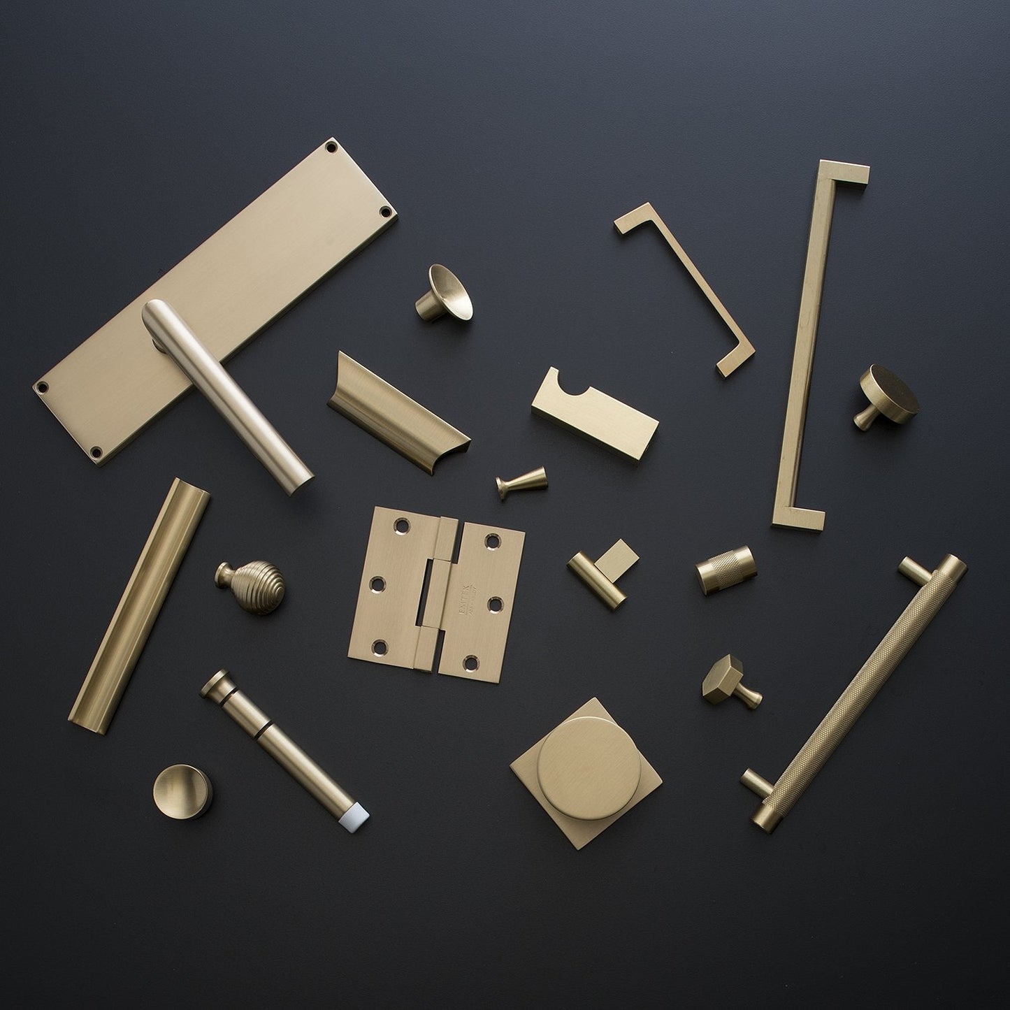 Top view of Knurled Pull and coordinating brass hardware arranged on a dark background