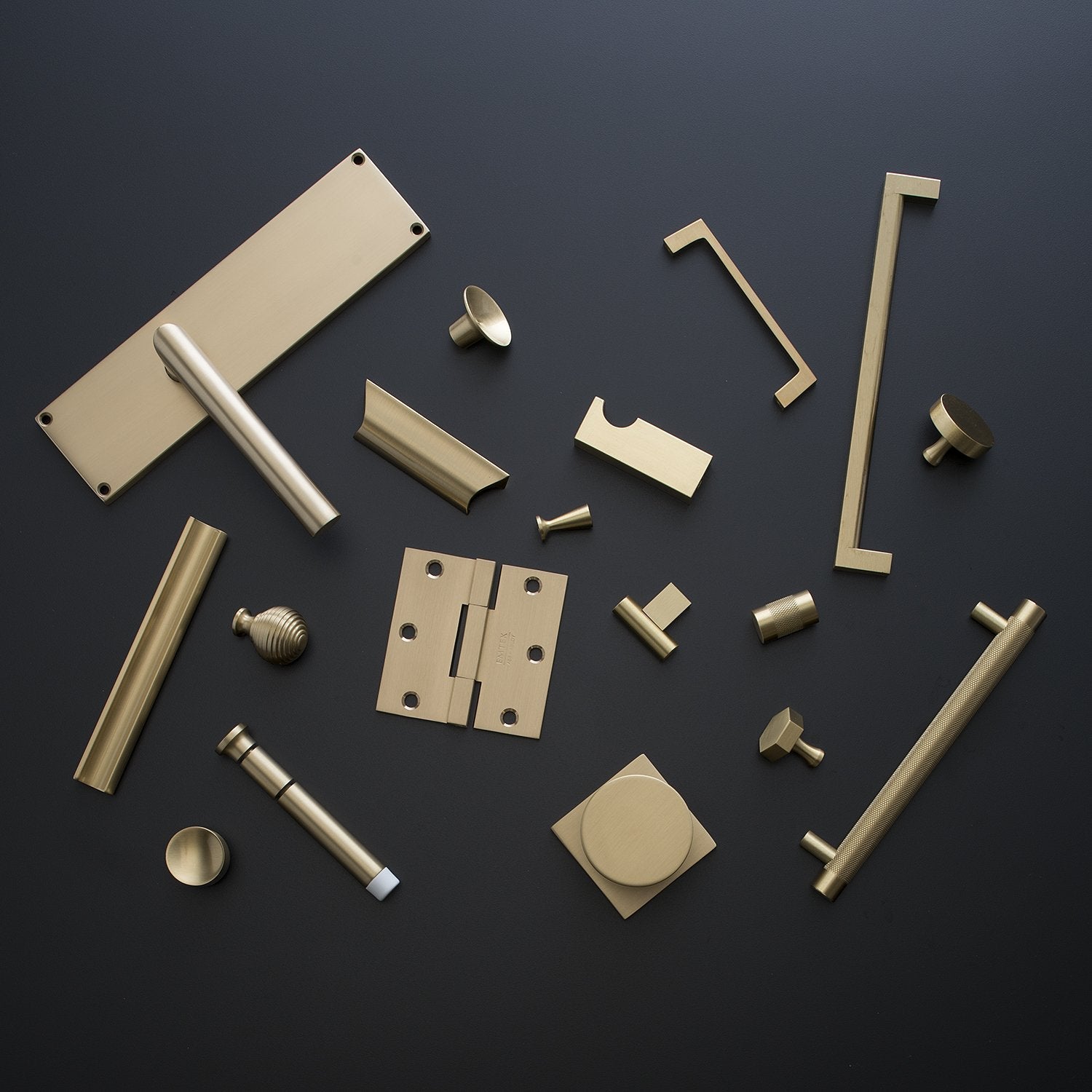 Top view of Edgecliff Pull hardware showcasing brass pulls, knobs, and hinges on a dark background