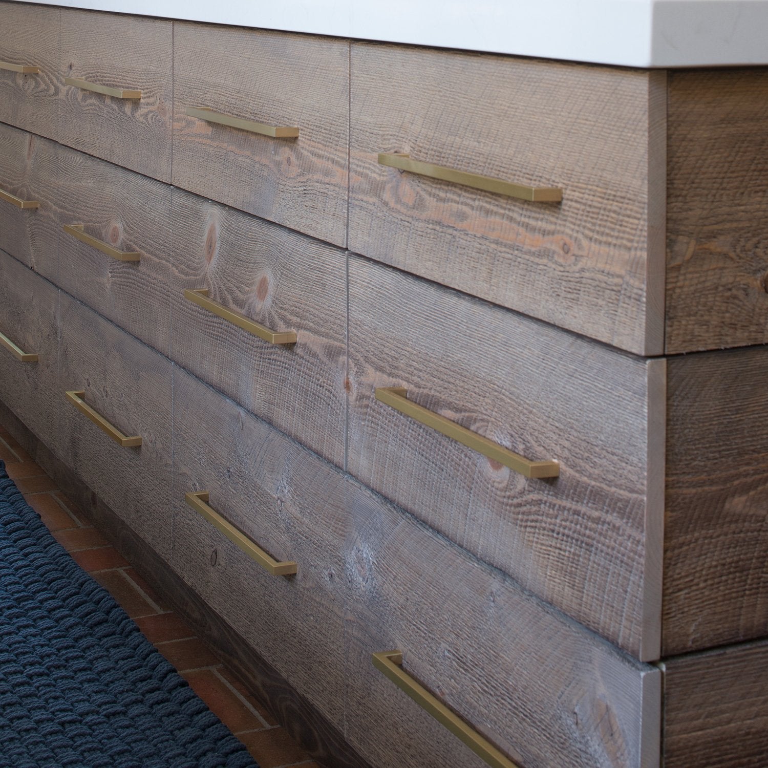Angled view of Edgecliff Appliance Pull installed on textured wood cabinetry, showcasing its geometric design