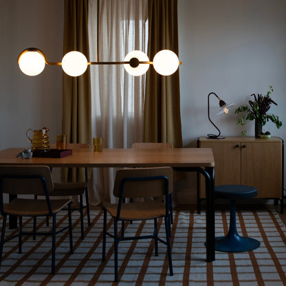 Plaid wool rug anchors a dining room with a wooden table, chairs, pendant light, and sideboard