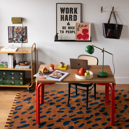 Green Isaac Desk Lamp stands on a desk in a colorful home office