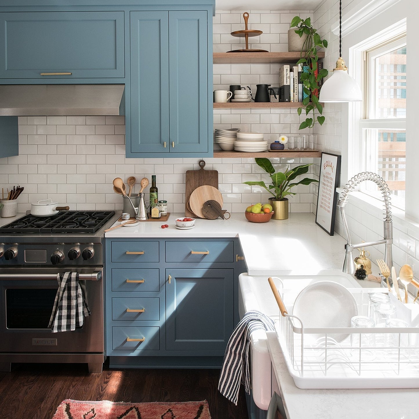 Blue kitchen cabinets featuring T Pull brass hardware beside a bright farmhouse sink