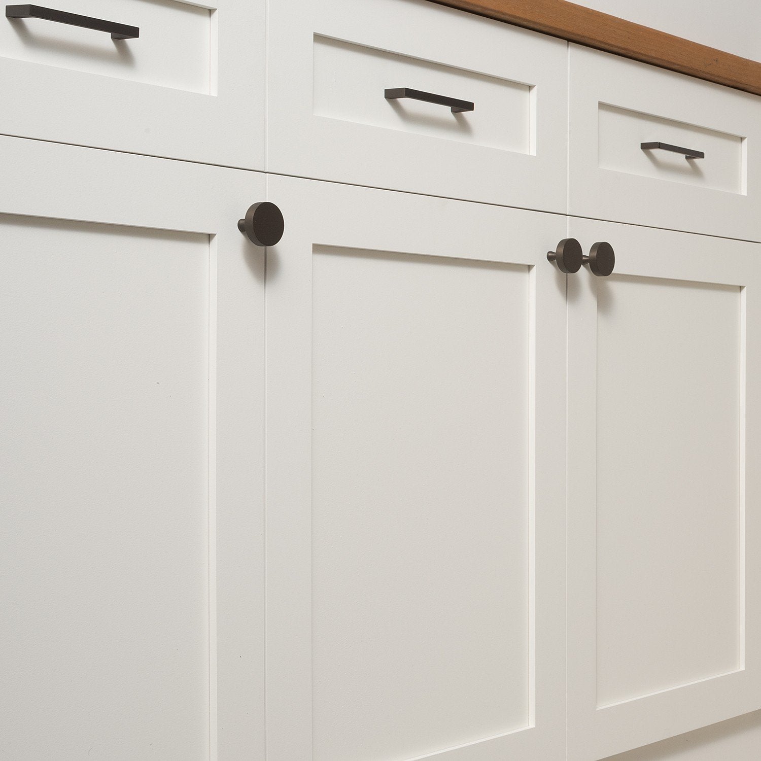 Riverwood knobs installed on white paneled cabinet doors alongside matching bar pulls