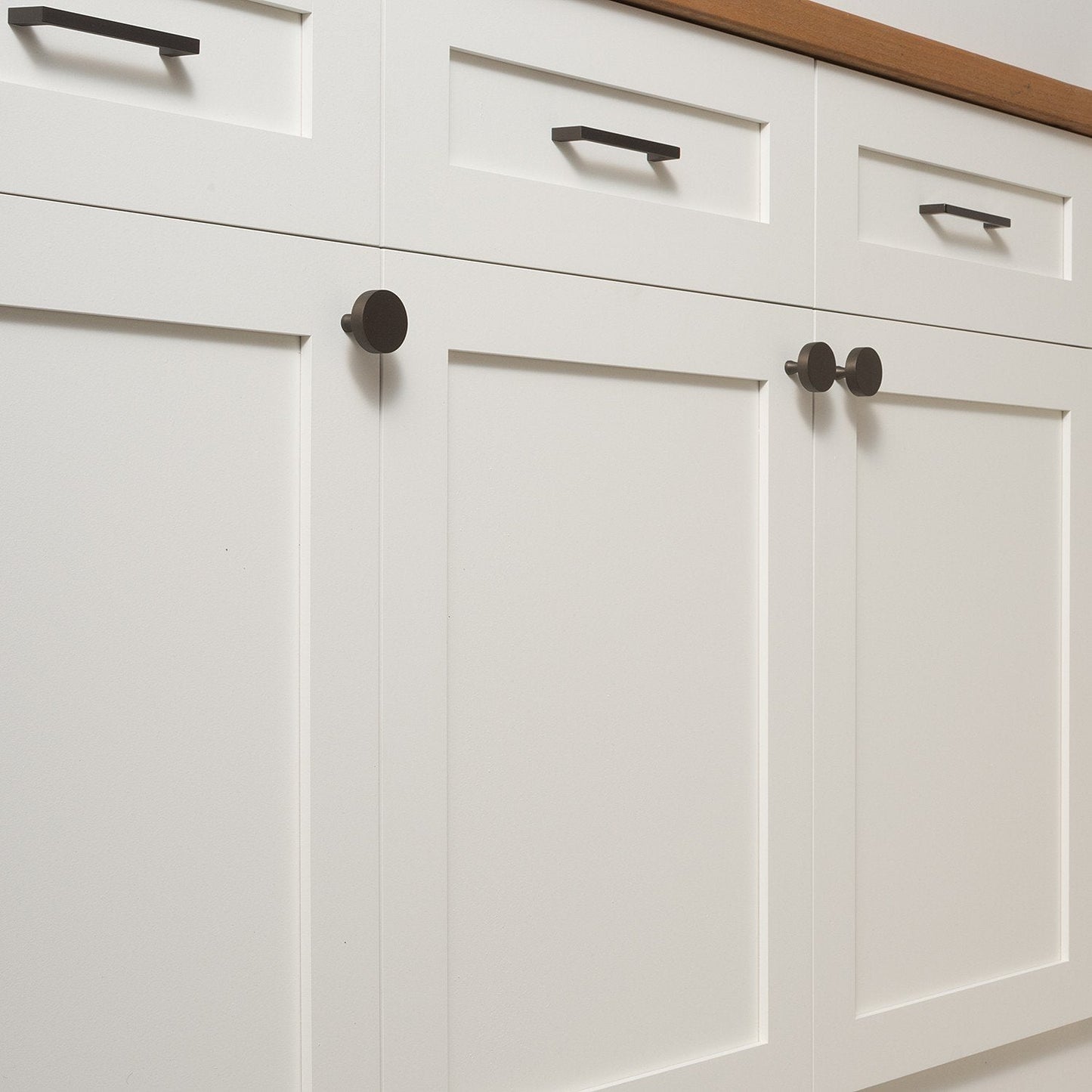Close-up of Greenwood Pull showcasing its thin profile on white paneled cabinetry