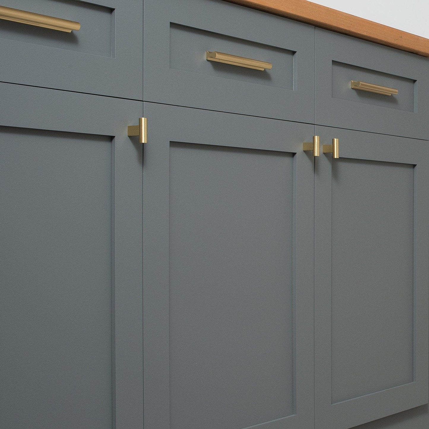 Front view of T Pull showcasing solid brass hardware on gray paneled cabinetry