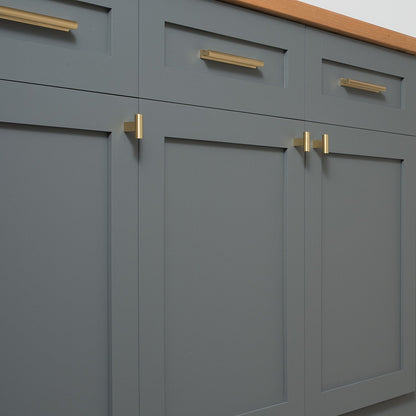 Front view of T Pull showcasing solid brass hardware on gray paneled cabinetry