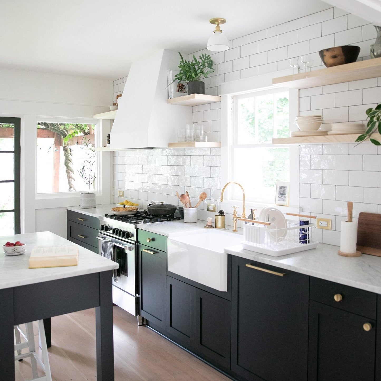 Kitchen with dark cabinets featuring round brass knobs, white countertops, and a white tiled backsplash