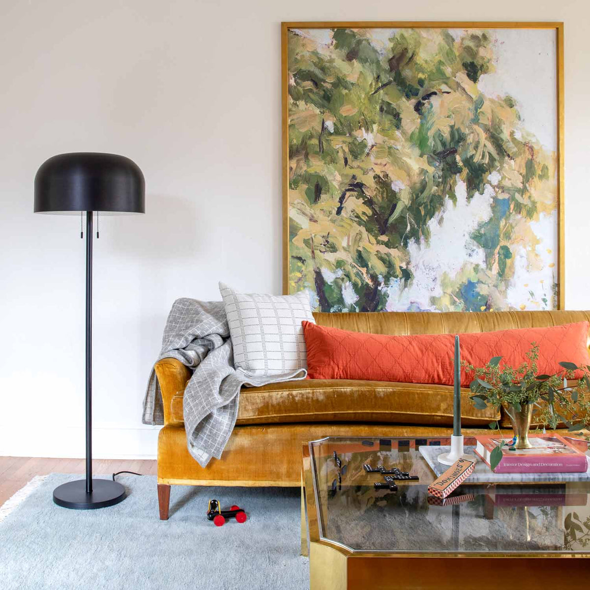 Living room with a Fog Mesa wool rug, mustard sofa, black floor lamp, and framed artwork