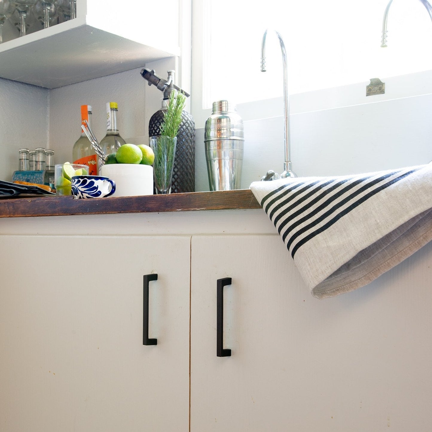Greenwood pulls installed on white cabinetry in a styled kitchen
