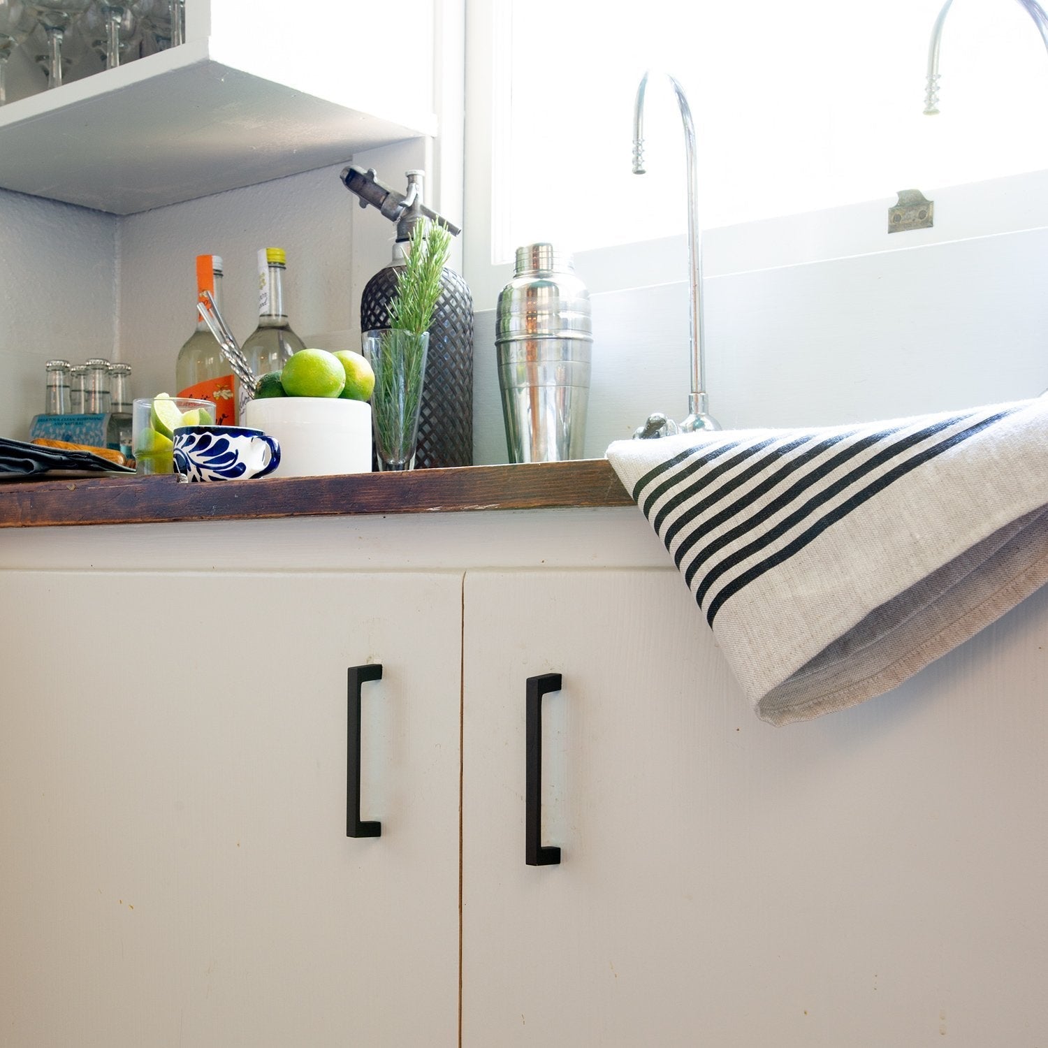 Greenwood pulls installed on white cabinetry in a styled kitchen
