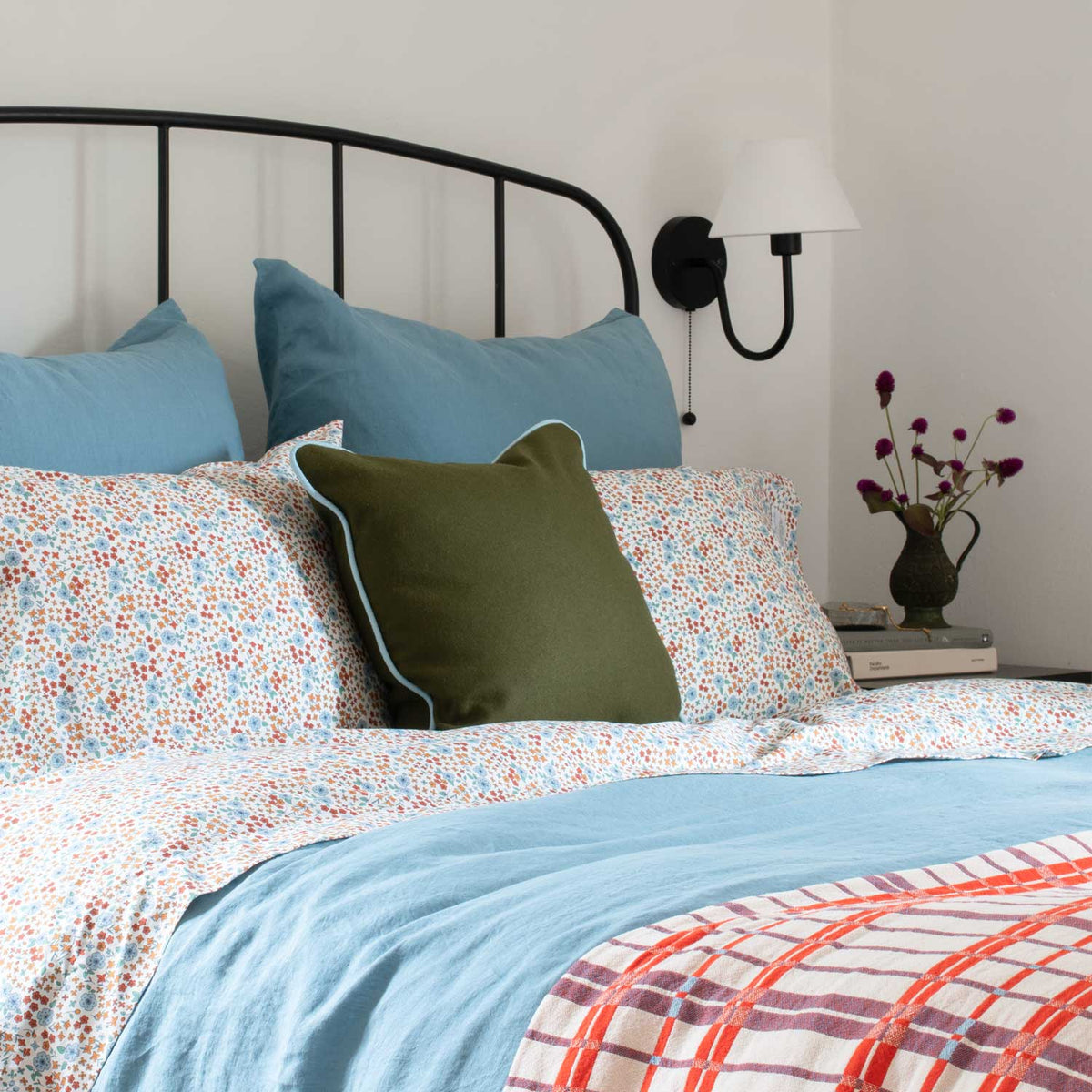 Styled view of Shelburne Coverlet showcasing its colorful floral pattern on a bed with blue bedding