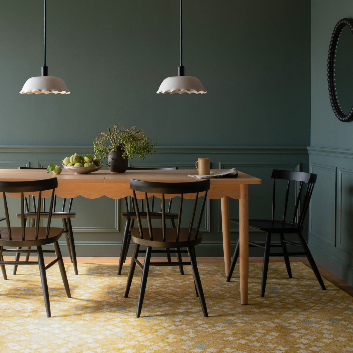 Sundrop rug beneath a dining table and chairs in a dark green dining room