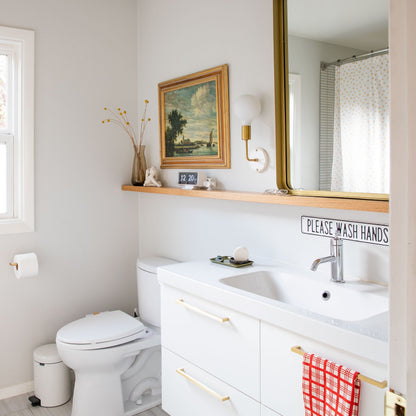 Gold Edgecliff appliance pulls installed on a white bathroom vanity in a bright bathroom
