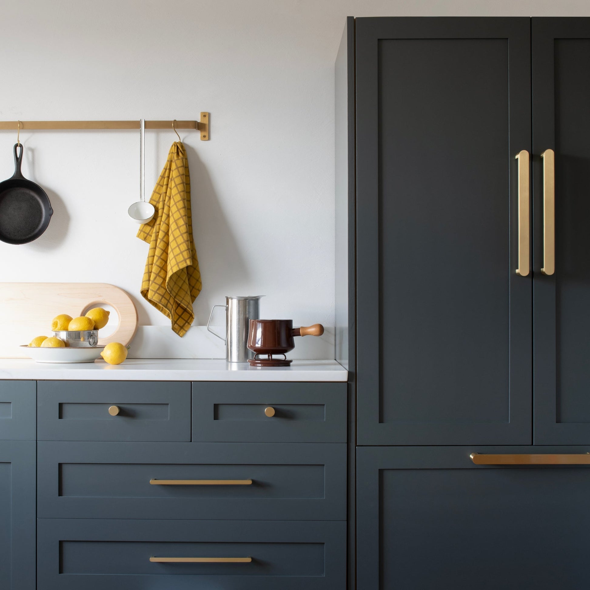 Front view of Cove Pull showcasing its gold-tone finish on dark kitchen cabinetry