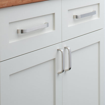 Close-up of Cascade Pull showcasing curved silver handles on white paneled cabinets