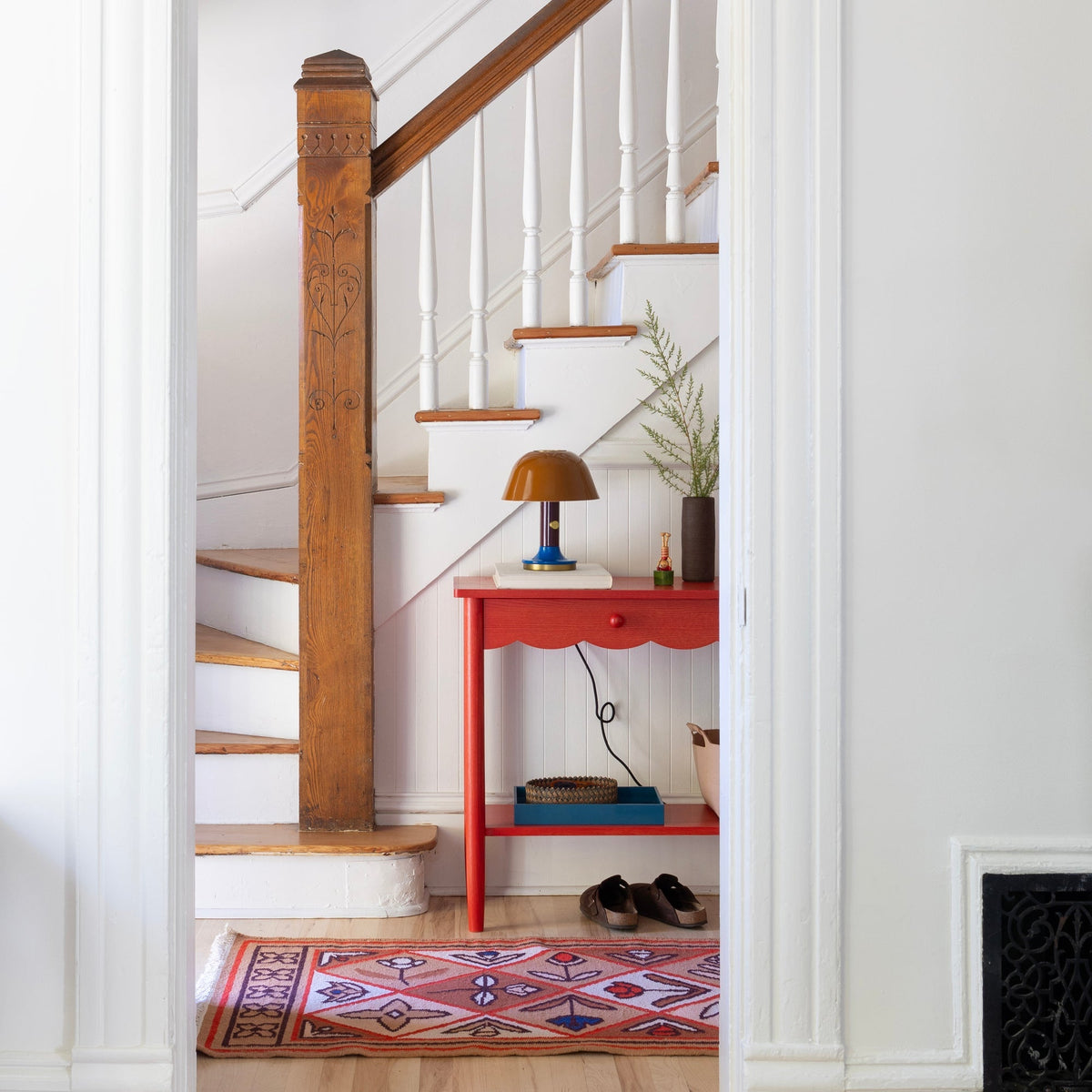 Pink Linnea wool flatweave rug with geometric motifs displayed in a bright hallway beneath a staircase