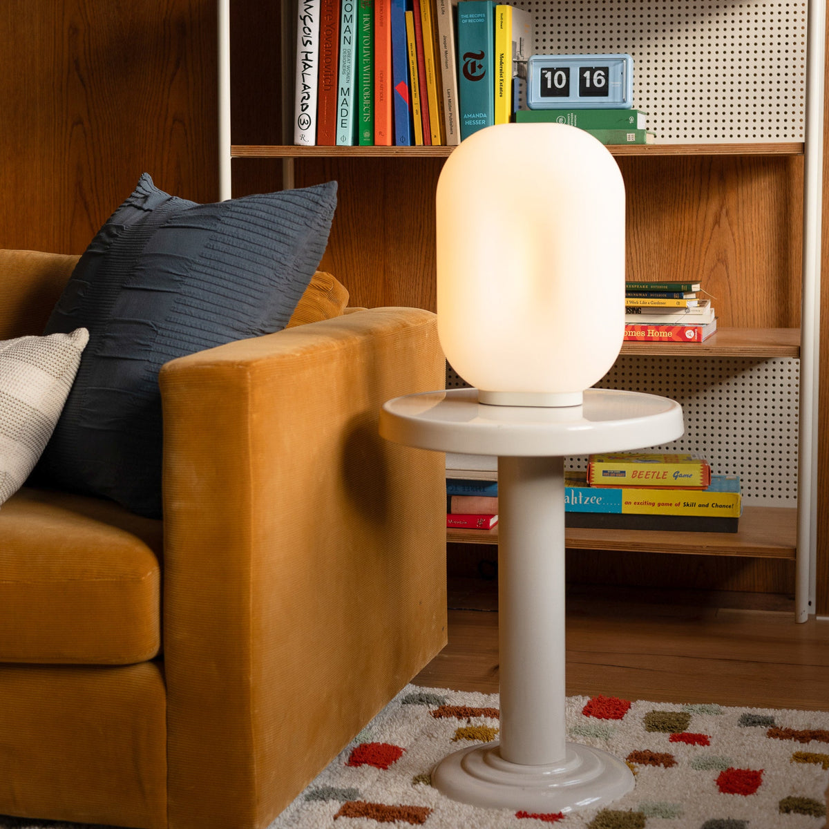 Pixel rug rests beneath a white table beside a mustard sofa in a cozy wood-paneled living room