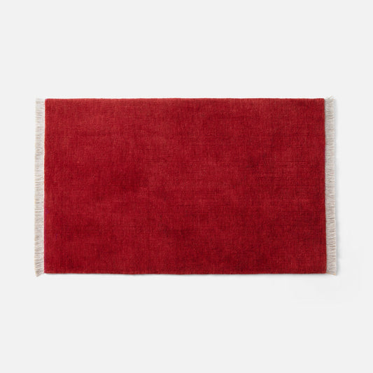Flat lay of Mesa wool rug showcasing currant red wool pile and natural fringe on white background