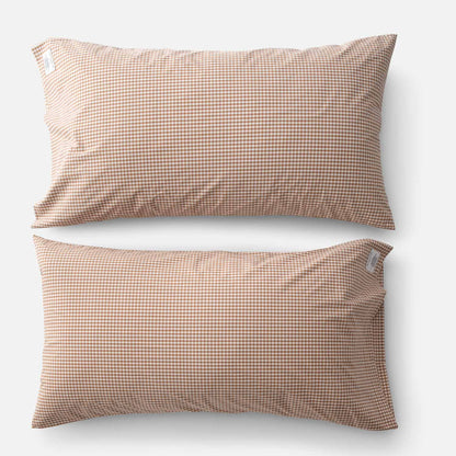 Top-down view of two Gingham percale pillowcases showcasing small tan gingham check on white background