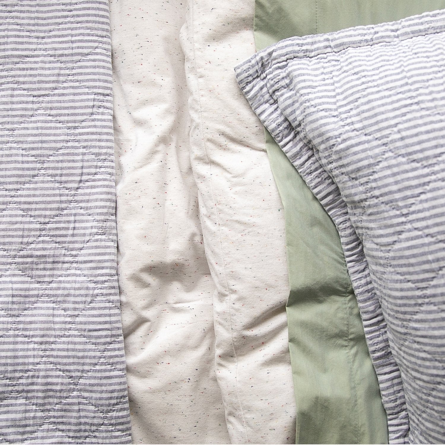 Close-up of Diamond Ticking Quilted Pillow Sham showing gray-and-white ticking stripes on cream and sage bedding