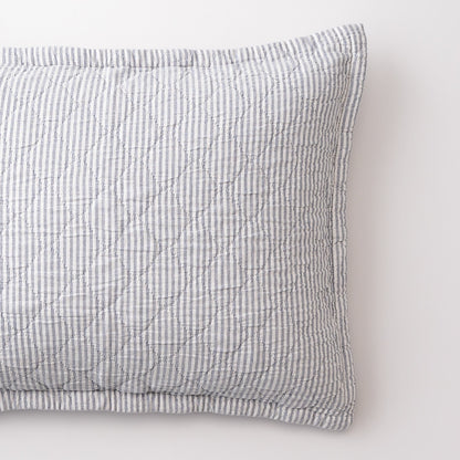 Close-up of Diamond Ticking Quilted Pillow Sham showing narrow blue and white ticking stripes and diamond quilting on a white background